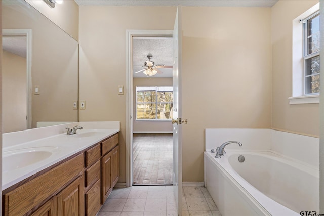 bathroom featuring ceiling fan, tile patterned floors, a textured ceiling, a bathtub, and vanity