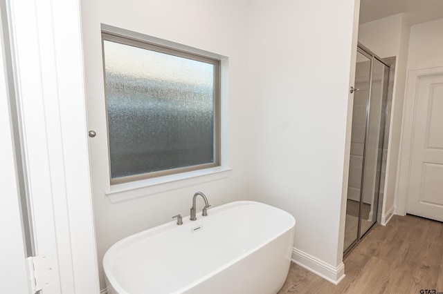 full bathroom featuring a soaking tub, baseboards, a shower stall, and wood finished floors