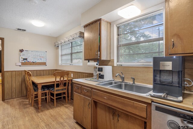 9961 Creek Bend Dr, Tyler, TX 75707 - kitchen with stainless steel dishwasher, a sink, a textured ceiling, light countertops, and light wood-style flooring