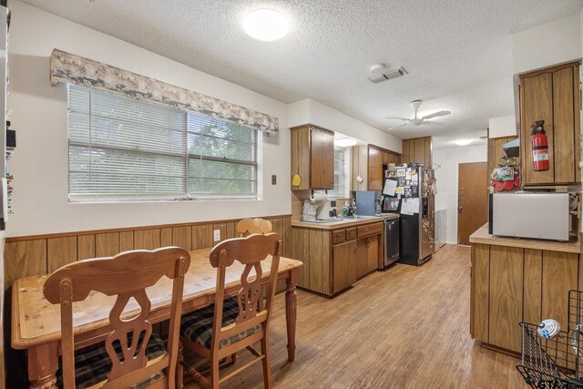 9961 Creek Bend Dr, Tyler, TX 75707 - kitchen with stainless steel refrigerator with ice dispenser, brown cabinetry, ceiling fan, white microwave, and light countertops