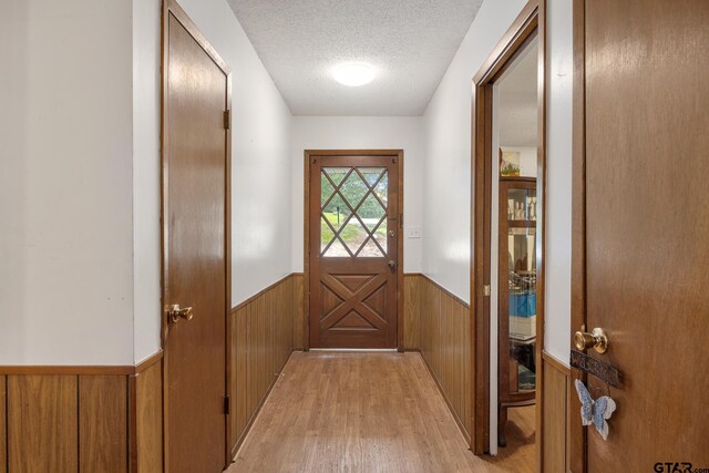 9961 Creek Bend Dr, Tyler, TX 75707 - doorway with wainscoting, light wood-style floors, a textured ceiling, and wooden walls