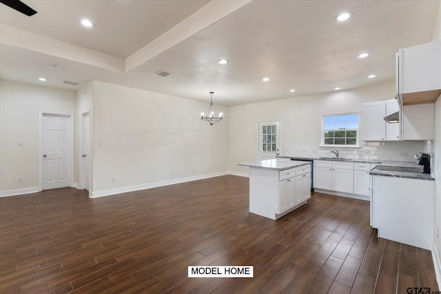 kitchen featuring dark wood-type flooring, a center island, hanging light fixtures, black range, and white cabinetry