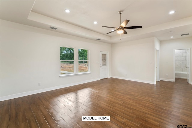 unfurnished room featuring dark hardwood / wood-style floors, a raised ceiling, and ceiling fan