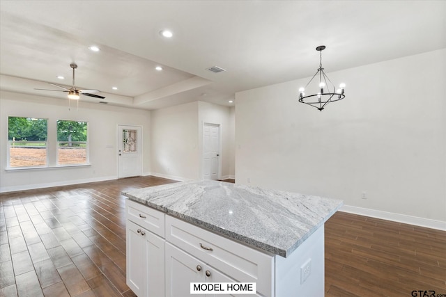 kitchen with dark hardwood / wood-style flooring, decorative light fixtures, light stone counters, and white cabinets