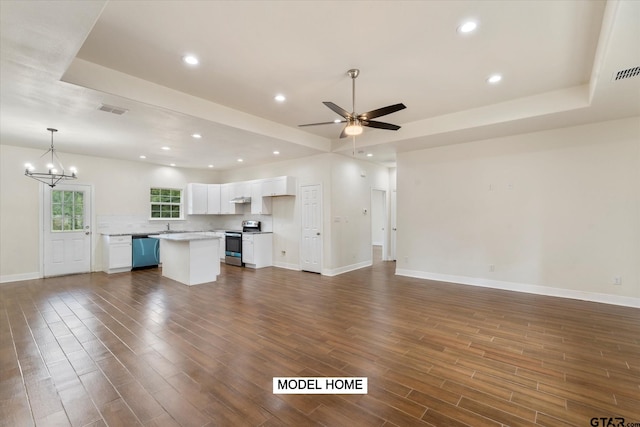 unfurnished living room with ceiling fan with notable chandelier, a raised ceiling, and dark hardwood / wood-style flooring