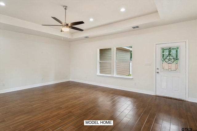 spare room featuring ceiling fan, dark hardwood / wood-style floors, and a raised ceiling