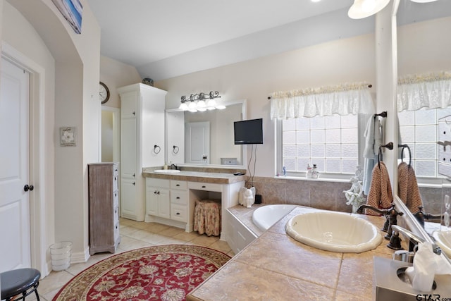 bathroom featuring tile patterned floors, vanity, and tiled bath