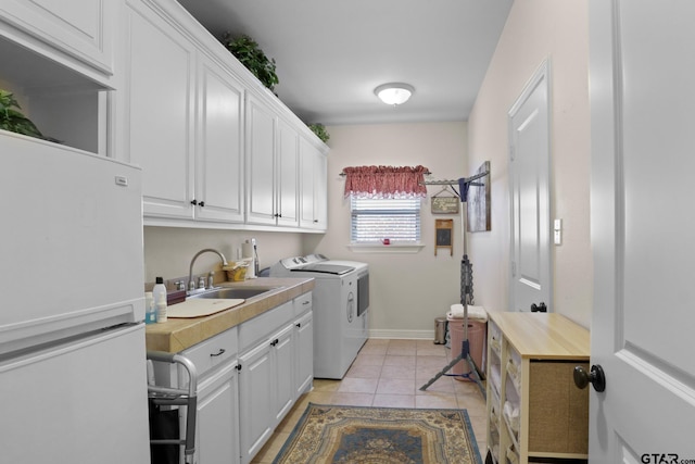 washroom with cabinets, washing machine and dryer, sink, and light tile patterned floors