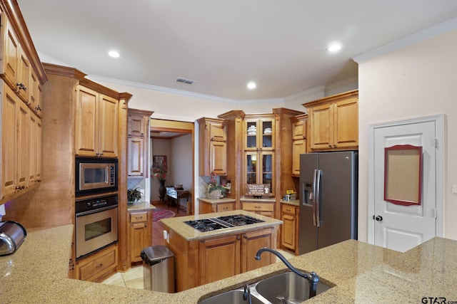 kitchen with sink, appliances with stainless steel finishes, light stone counters, ornamental molding, and a kitchen island