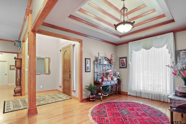 interior space with a raised ceiling, ornamental molding, and hardwood / wood-style floors