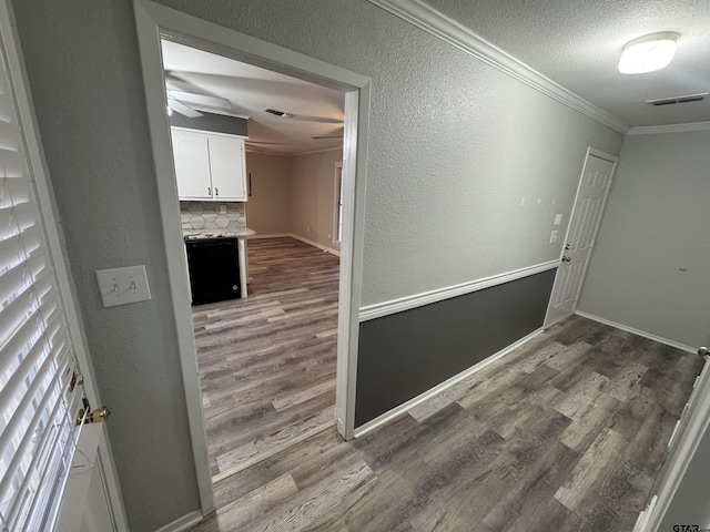 corridor featuring crown molding, hardwood / wood-style floors, and a textured ceiling