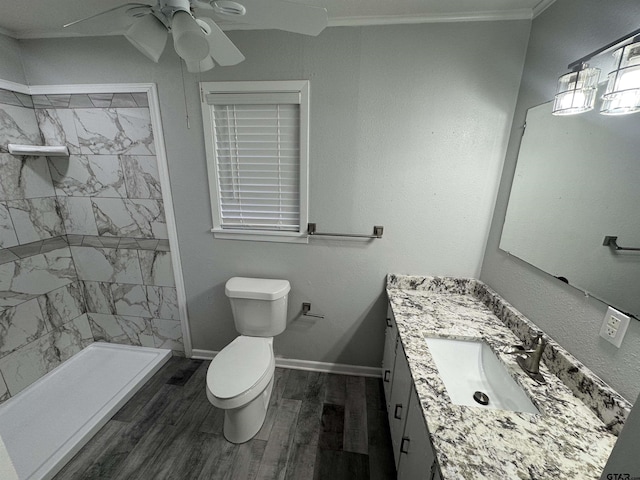 bathroom with crown molding, hardwood / wood-style flooring, tiled shower, vanity, and toilet