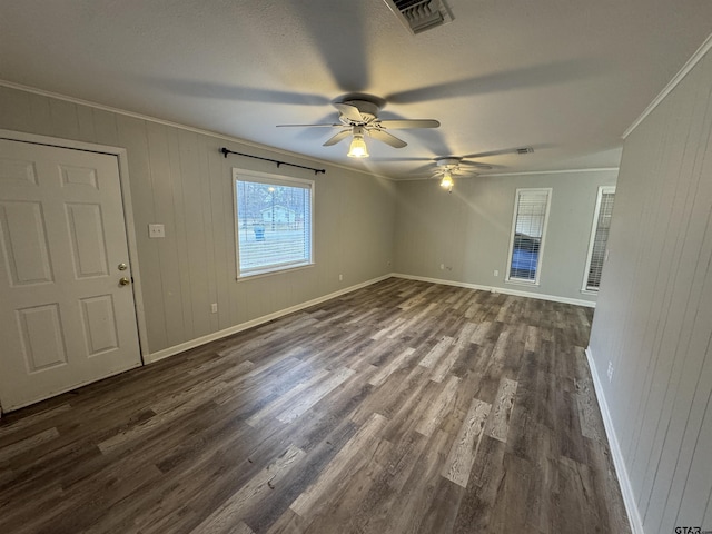 empty room with ceiling fan, ornamental molding, dark hardwood / wood-style floors, and wood walls