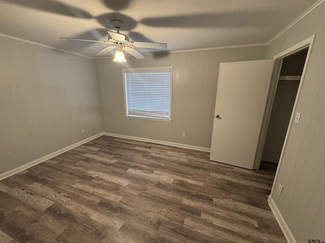 unfurnished bedroom with ceiling fan, ornamental molding, dark hardwood / wood-style flooring, and wood walls