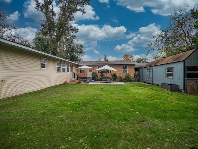 rear view of house with a patio, a lawn, and a storage shed