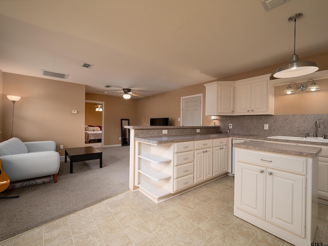 kitchen featuring hanging light fixtures, light colored carpet, and white cabinets