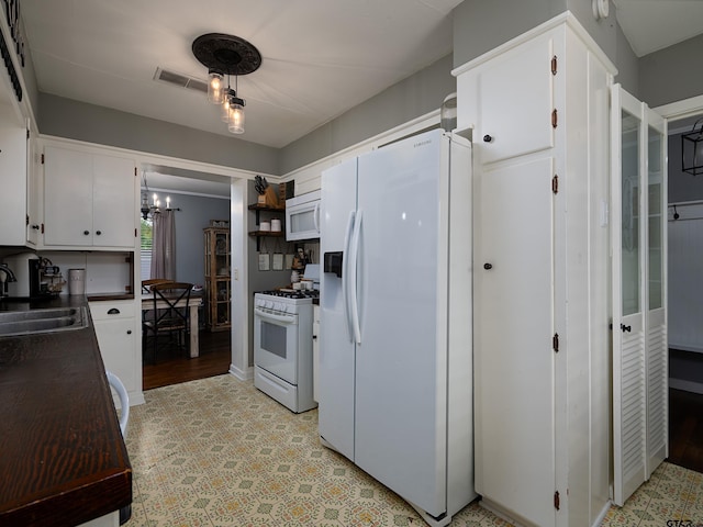 kitchen featuring sink, a chandelier, white cabinets, and white appliances