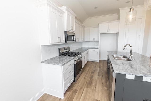 kitchen featuring light hardwood / wood-style floors, white cabinets, sink, appliances with stainless steel finishes, and decorative light fixtures