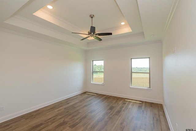 empty room featuring dark hardwood / wood-style floors, crown molding, a tray ceiling, and ceiling fan