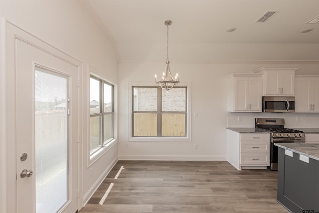 kitchen with white cabinets, light wood-type flooring, appliances with stainless steel finishes, and decorative light fixtures