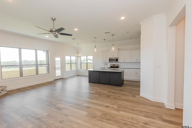 kitchen featuring stainless steel appliances, a center island with sink, decorative light fixtures, white cabinets, and light wood-type flooring