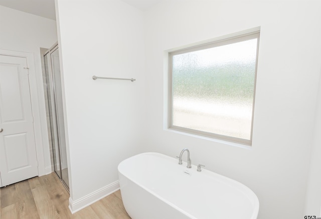 bathroom featuring shower with separate bathtub, a wealth of natural light, and hardwood / wood-style floors