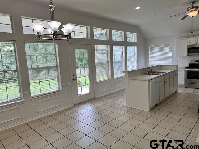 1712 Onyx Cv, Whitehouse, TX 75791 - kitchen featuring stainless steel appliances, light tile patterned floors, vaulted ceiling, light countertops, and white cabinetry