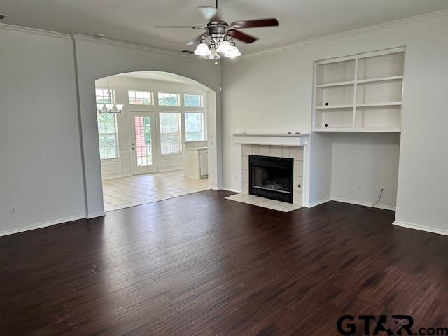 1712 Onyx Cv, Whitehouse, TX 75791 - unfurnished living room featuring ornamental molding, arched walkways, ceiling fan, a fireplace, and wood finished floors