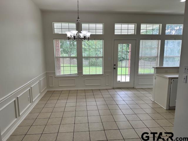 1712 Onyx Cv, Whitehouse, TX 75791 - doorway to outside featuring a decorative wall, plenty of natural light, a chandelier, light tile patterned floors, and wainscoting