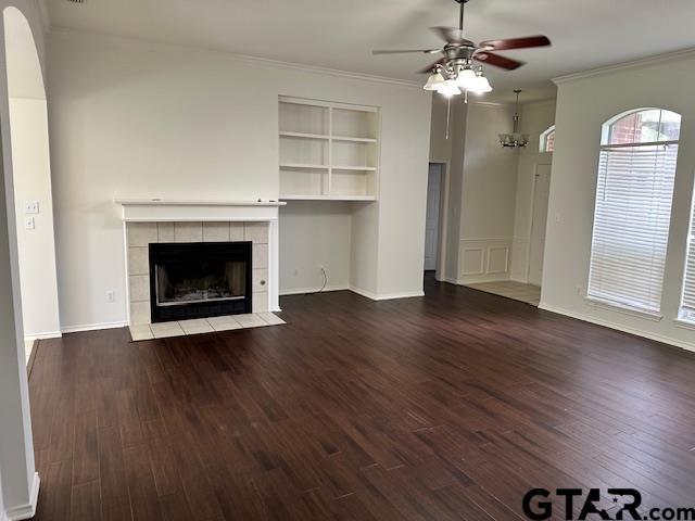 1712 Onyx Cv, Whitehouse, TX 75791 - unfurnished living room featuring a ceiling fan, a tiled fireplace, wood finished floors, crown molding, and built in features