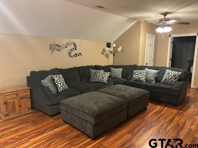 living room with dark wood-type flooring, ceiling fan, and vaulted ceiling