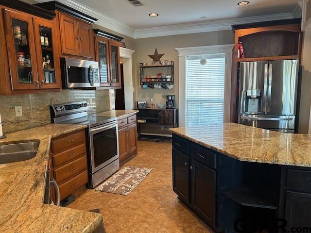 kitchen with tasteful backsplash, appliances with stainless steel finishes, sink, and light stone counters