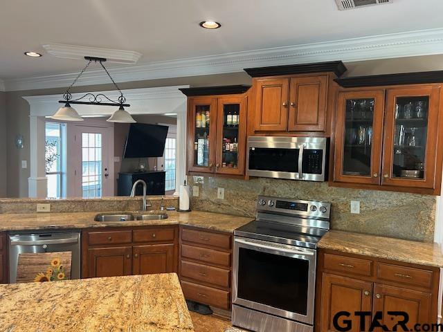 kitchen featuring appliances with stainless steel finishes, sink, hanging light fixtures, crown molding, and light stone countertops