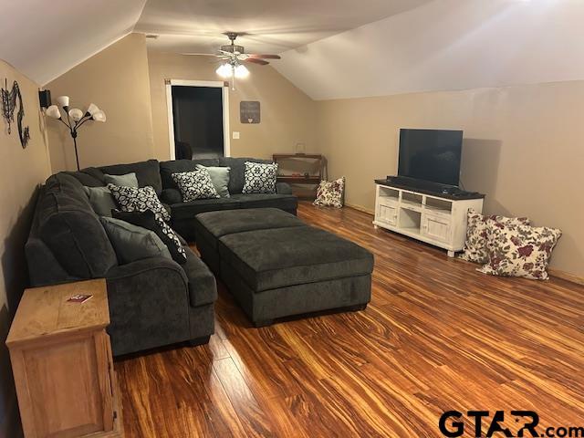 living room with dark wood-type flooring, ceiling fan, and vaulted ceiling