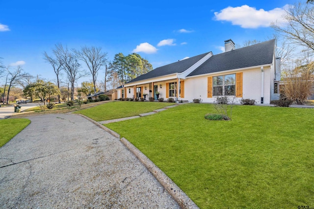 ranch-style house featuring a front yard, roof with shingles, and a chimney