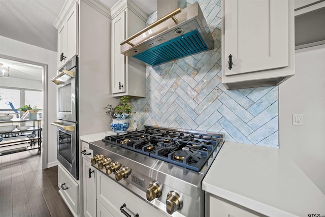 kitchen with range hood, stainless steel double oven, gas stovetop, light countertops, and tasteful backsplash