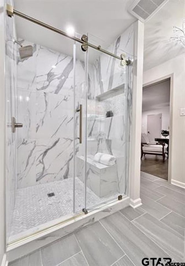 bathroom with a marble finish shower and visible vents