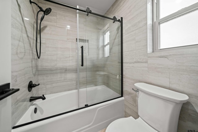 bathroom featuring tile walls, toilet, and enclosed tub / shower combo