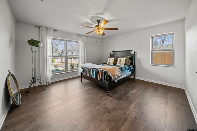 bedroom featuring multiple windows, dark wood-type flooring, baseboards, and ceiling fan