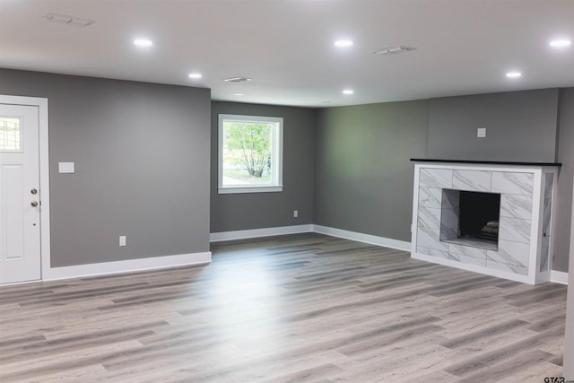 unfurnished living room with recessed lighting, baseboards, wood finished floors, and a tile fireplace