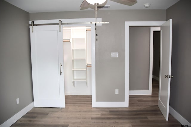 613 Northgate Rd, Hideaway, TX 75771 - unfurnished bedroom with wood finished floors, a closet, visible vents, a barn door, and baseboards