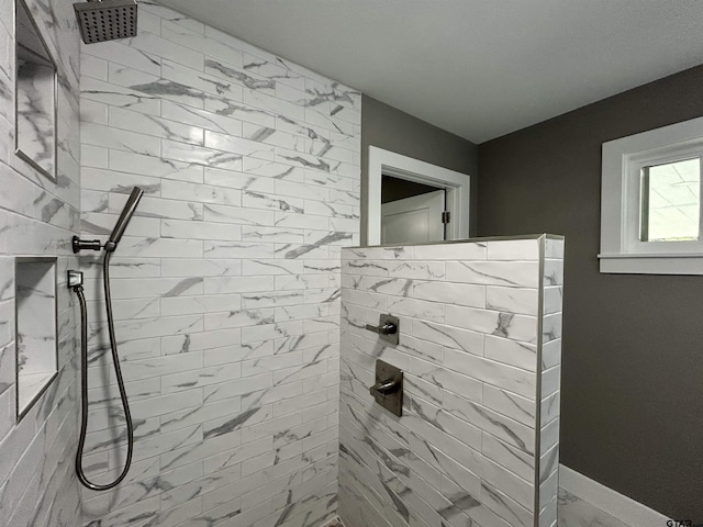 full bathroom featuring a tile shower and marble finish floor