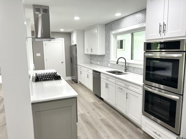 kitchen with island range hood, light countertops, white cabinets, light wood-style flooring, and stainless steel appliances