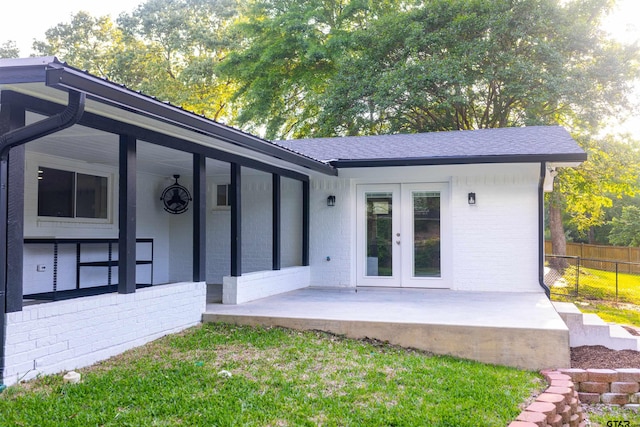 back of house with brick siding, fence, french doors, and roof with shingles