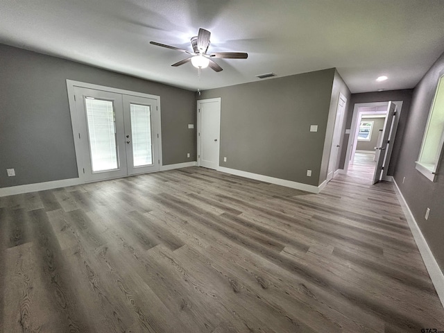 unfurnished living room with french doors, a ceiling fan, baseboards, wood finished floors, and visible vents