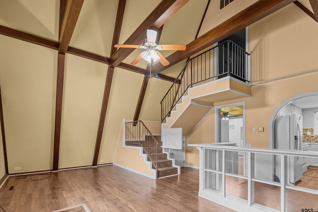 staircase featuring a high ceiling, ceiling fan, and hardwood / wood-style floors