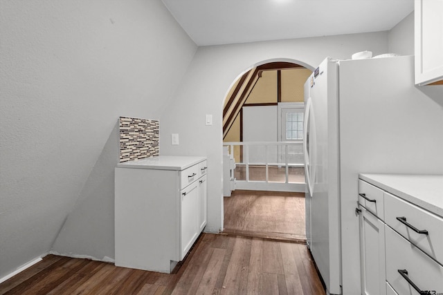 kitchen with white cabinets, dark hardwood / wood-style floors, white fridge, and tasteful backsplash