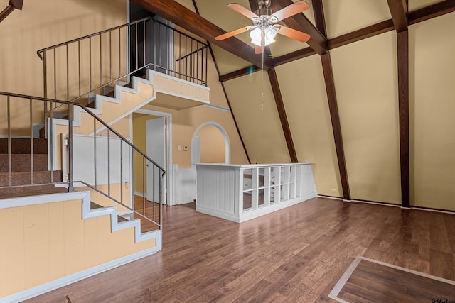 stairs with hardwood / wood-style floors, a towering ceiling, and ceiling fan