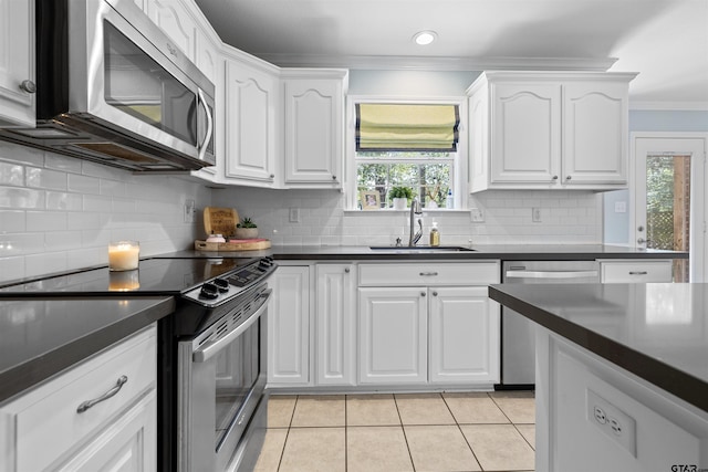 4918 Pine Knl, Tyler, TX 75703 - kitchen with stainless steel appliances, a sink, crown molding, light tile patterned flooring, and dark countertops