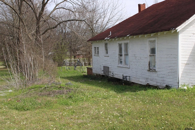 view of property exterior featuring a yard, cooling unit, and a chimney